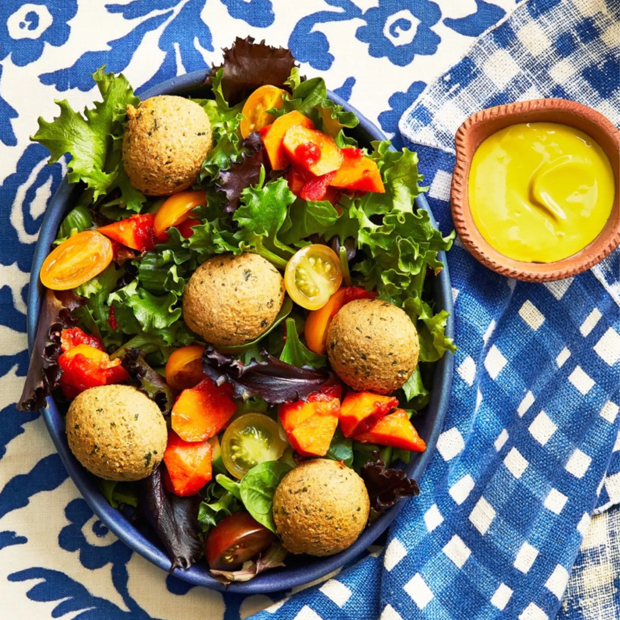 A closeup of a bowl of Falafel Mezze on a white and blue tablecloth for upcoming menu provided by Laroot World, an organic, local, gluten free New York City flexitarian, pescatarian, carnitarian, vegan, and vegetarian meal delivery service