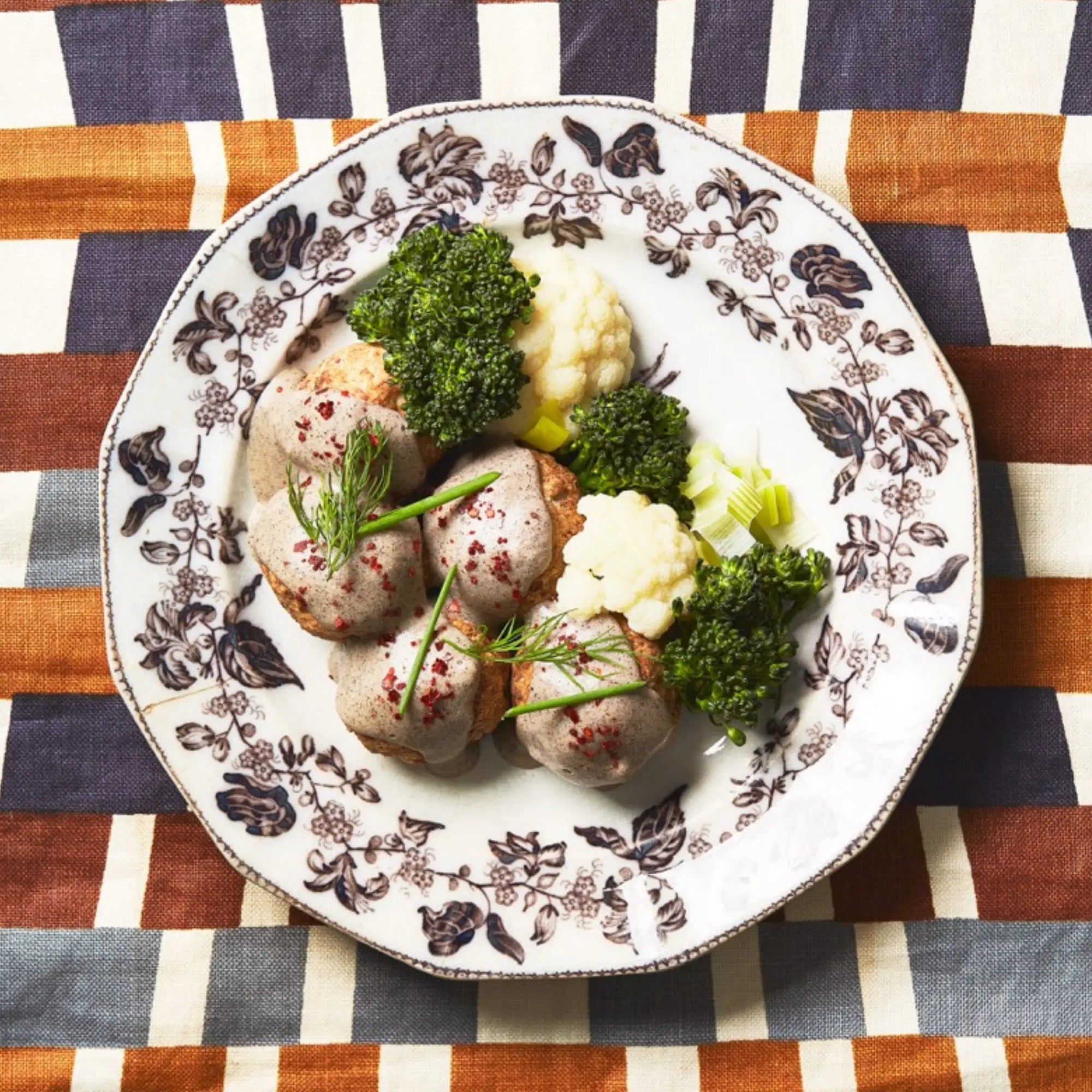 A closeup of a bowl of Akvavit Meatballs on a decorated tablecloth for upcoming menu provided by Laroot World, an organic, local, gluten free New York City flexitarian, pescatarian, carnitarian, vegan, and vegetarian meal delivery service 