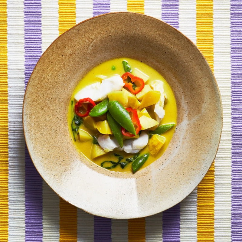 A closeup of a plate with Kari Malay on a yellow and purple tablecloth for upcoming menu provided by Laroot World, an organic, local, gluten free New York City flexitarian, pescatarian, carnitarian, vegan, and vegetarian meal delivery service 