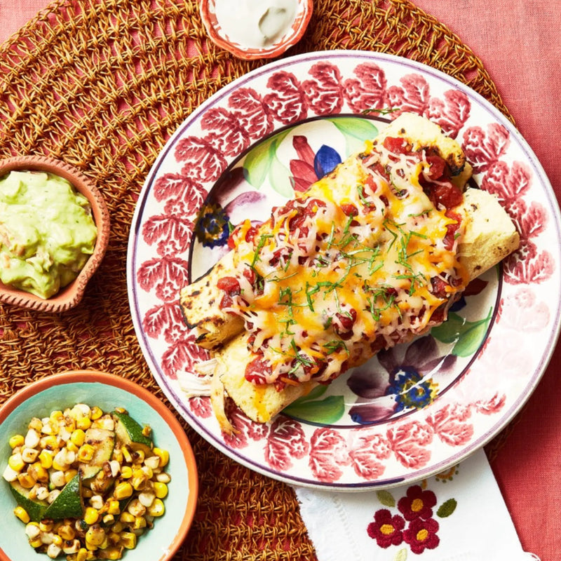 A closeup of a plate with Chicken Enchiladas on a red tablecloth for upcoming menu provided by Laroot World, an organic, local, gluten free New York City flexitarian, pescatarian, carnitarian, vegan, and vegetarian meal delivery service 